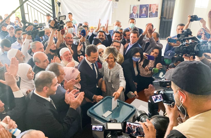 Syria's President Bashar Assad and his wife Asma cast their votes during the country's presidential elections at a polling station in Douma, Syria, May 26, 2021. (photo credit: FIRAS MAKDESI/REUTERS)
