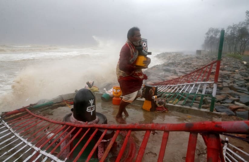 A Hindu priest carries an idol of Lord Jagannath from a seafront temple to a safer place ahead of Cyclone Yaas in Balasore district in the eastern state of Odisha India, May 26, 2021. (photo credit: REUTERS/RUPAK DE CHOWDHURI)