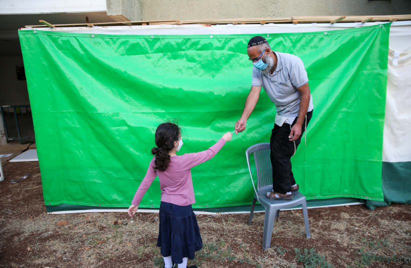 CONSTRUCTING THE sukkah: Are women exempt from sitting in it?  (photo credit: DAVID COHEN/FLASH 90)
