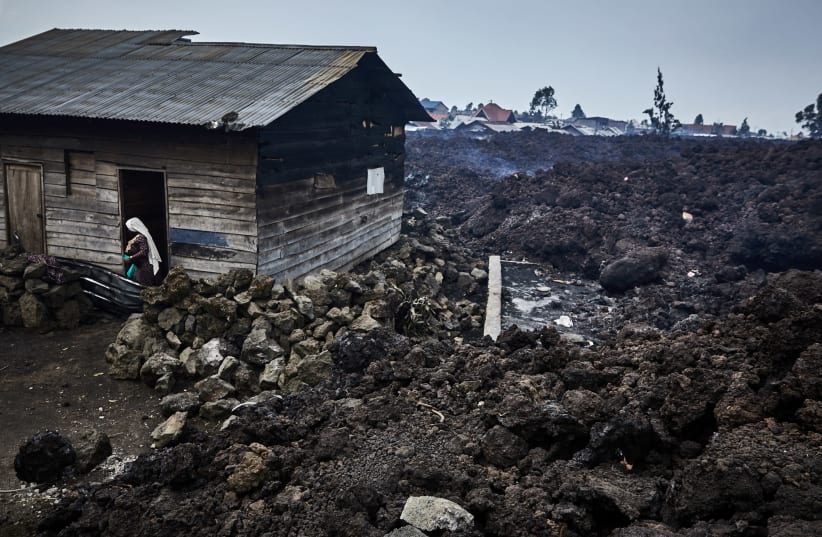 A woman prepares to evacuate from recurrent earth tremors as aftershocks after homes were covered with lava deposited by the eruption of Mount Nyiragongo near Goma (photo credit: REUTERS)