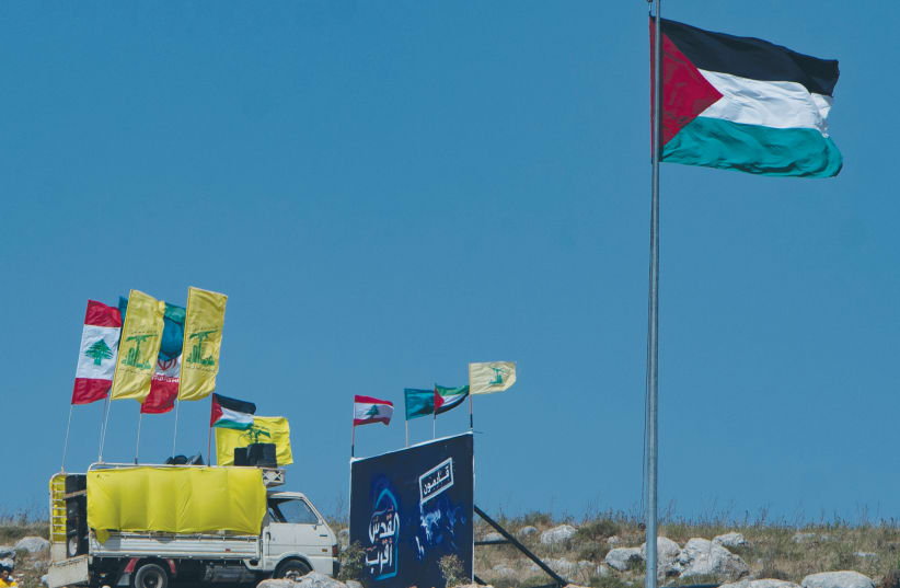 PALESTINIAN AND Lebanese flags flutter during a solidarity protest last week at the Lebanese border with Israel, as seen from the Israeli side. (photo credit: BASEL AWIDAT/FLASH90)