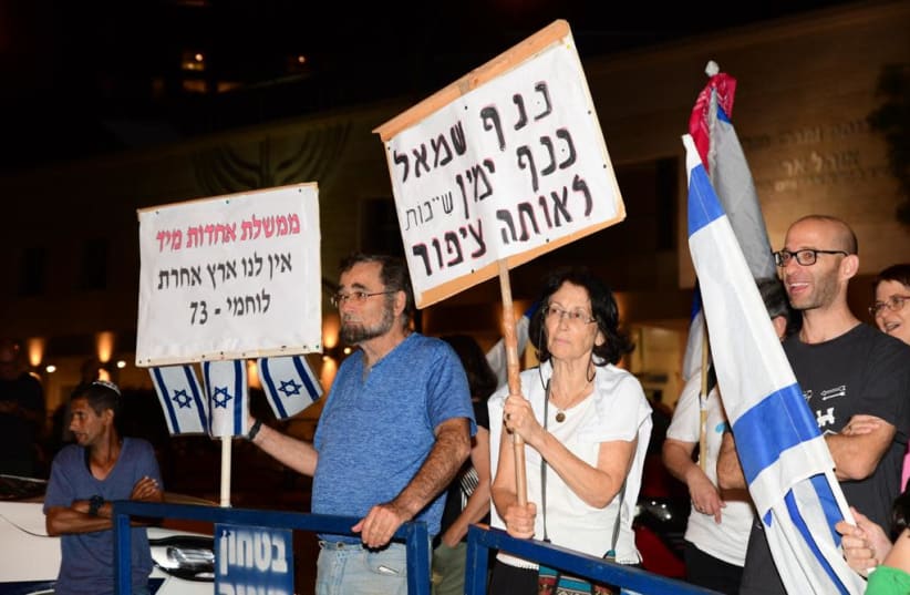 A protester holds a sign reading 'the left wing and the right wing belong to the same bird,' at a protest outside the home of Ayelet Shaked, May 29, 2021 (photo credit: AVSHALOM SASSONI)