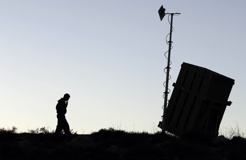 An Israeli soldier walks next to an Iron Dome missile interceptor battery after it is being positioned on the outskirts of Jerusalem, September 8, 2013.  (photo credit: REUTERS/AMMAR AWAD)