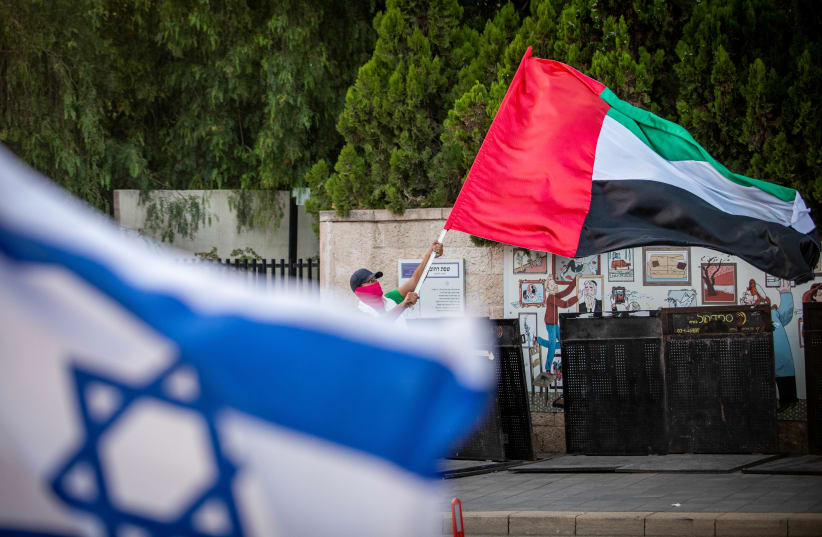 A man waves a giant United Arab Emirates flag outside the Prime Minister's official residence in Jerusalem on August 19, 2020 (photo credit: YONATAN SINDEL/FLASH 90)
