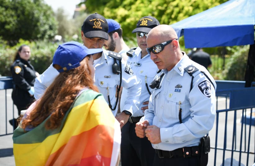 Police officers are seen with an activist at Jerusalem's Gay Pride Parade, on June 3, 2021. (photo credit: POLICE SPOKESPERSON'S UNIT)