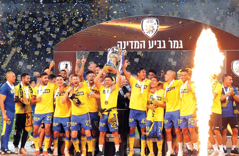MACCABI TEL AVIV celebrates on the pitch with the trophy after beating Hapoel Tel Aviv 2-1 in extra time on Wednesday at Bloomfield to win the Israel State Cup. (photo credit: BERNEY ARDOV)