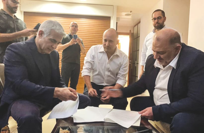 YESH ATID leader Yair Lapid, Yamina head Naftali Bennett and Ra’am leader Mansour Abbas sign coalition agreements at the Kfar Maccabiah hotel Wednesday night.  (photo credit: RA'AM)