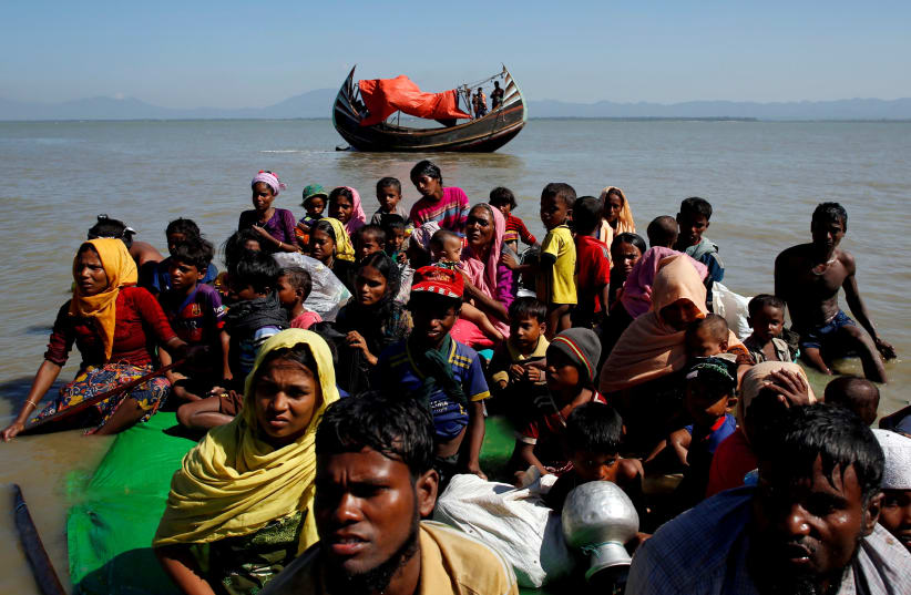Rohingya refugees sit on a makeshift boat as they get interrogated by the Border Guard Bangladesh after crossing the Bangladesh-Myanmar border, at Shah Porir Dwip near Cox's Bazar (photo credit: REUTERS)