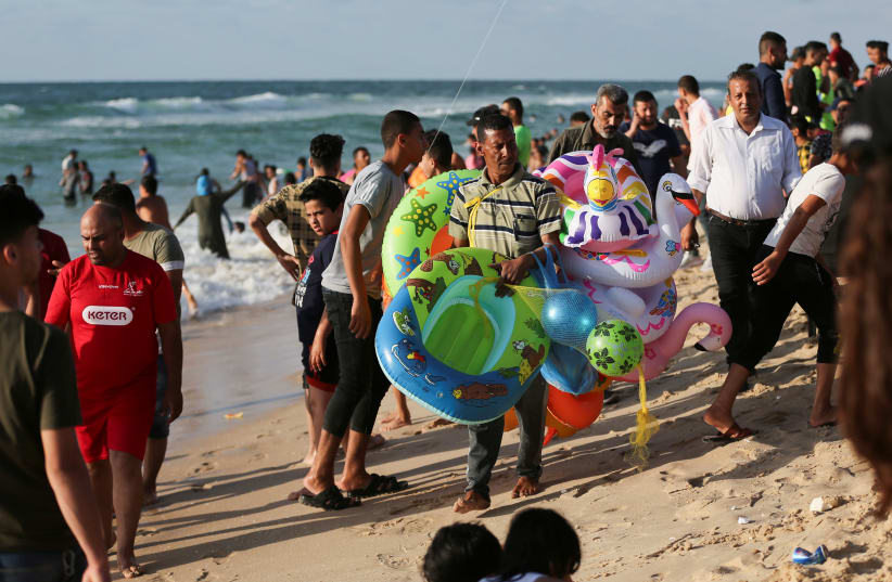 A MAN SELLS floats as Palestinians spend time at the beach in Khan Younis in the southern Gaza Strip June 4, 2021. (photo credit: REUTERS/IBRAHEEM ABU MUSTAFA)