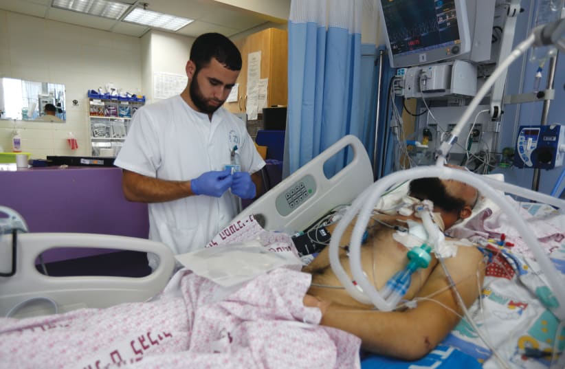AN ISRAELI NURSE tends to a severely wounded Syrian at the Western Galilee Hospital in Nahariya in 2013. (photo credit: BAZ RATNER/REUTERS)