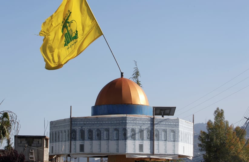 Hezbollah flag flies over a replica of Jerusalem's Dome of the Rock during a protest to express solidarity with the Palestinian people, in Kfar Kila near the border with Israel, southern Lebanon, May 14, 2021 (photo credit: REUTERS/AZIZ TAHER)