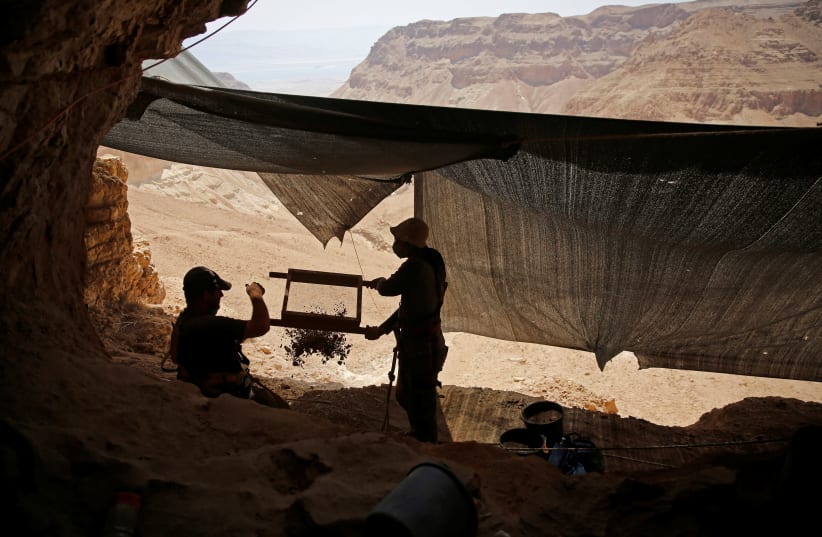 Volunteers with the Israeli Antique Authority work at the Cave of the Skulls, an excavation site in the Judean Desert near the Dead Sea, Israel June 1, 2016. (photo credit: REUTERS/RONEN ZEVULUN)