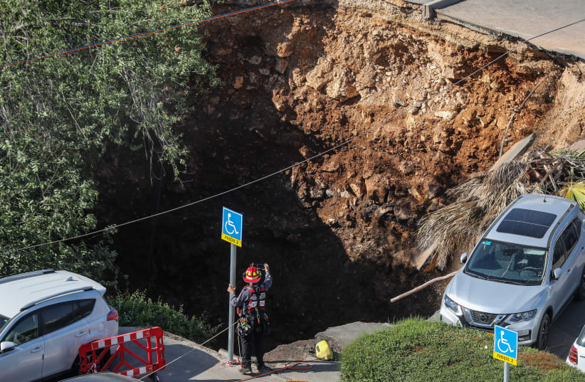 Fire and search- and rescue crews at the scene of where a parking lot collapsed into a giant sinkhole at the Shaare Tzedek Medical Hospital in Jerusalem on June 07, 2021. (photo credit: OLIVER FITOUSSI/FLASH90)