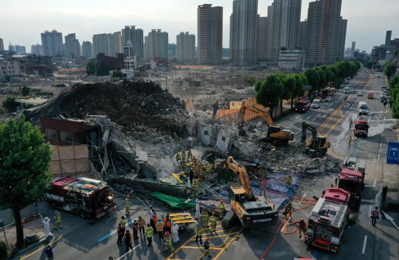 South Korean firefighters search for passengers from a bus trapped by the debris of a collapsed building in Gwangju, South Korea, June 9, 2021.  (photo credit: REUTERS)