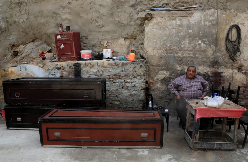 Mohamed Mahmoud, 65 years old a traditional undertaker looks on near lacquered wooden coffins and accessories at a working area in the Shobra district of Cairo, Egypt April 7, 2021.  (photo credit: REUTERS)