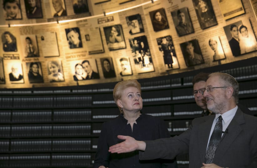 Former Lithuanian President Dalia Grybauskaite stands under pictures of Jews killed in the Holocaust during a visit to Yad Vashem’s Hall of Names in 2015 (photo credit: BAZ RATNER/REUTERS)