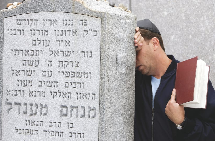 A MAN prays at the gravesite of the late Lubavitcher Rebbe, Rabbi Menachem Mendel Schneerson, as followers and admirers of Schneerson gather at his mausoleum in preparation for the 13th anniversary of his death at the Old Montefiore Cemetery in New York, on June 14, 2007. (photo credit: SHANNON STAPLETON / REUTERS)
