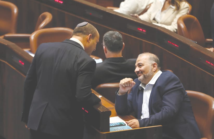 RIME MINISTER Naftali Bennett chats with United Arab List leader Mansour Abbas during a special session of the Knesset to swear in the new coalition government, in Jerusalem on Tuesday.  (photo credit: RONEN ZVULUN / REUTERS)