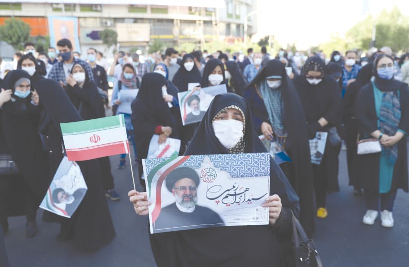 AN IRANIAN woman holds a picture of presidential candidate Ebrahim Raisi during an election rally in Tehran last week.  (photo credit: MAJID ASGARIPOUR/WANA/REUTERS)
