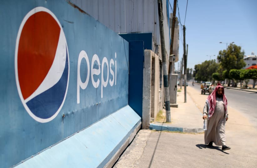 A Palestinian man walks past Gaza Pepsi factory for soft drinks in Gaza City June 21, 2021. (photo credit: MOHAMMED SALEM/REUTERS)