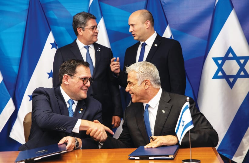 Prime Minister Naftali Bennett stands next to Honduran President Juan Orlando Hernandez, as Honduran Foreign Minister Lisandro Rosales and Foreign Minister Yair Lapid sign agreements at the Prime Minister’s Office in Jerusalem yesterday. (photo credit: HEIDI LEVINE/POOL)