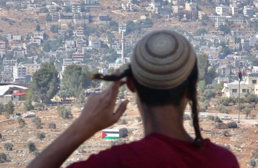 A young Israeli from the illegal Evyatar outpost looks out at the Palestinian village of Beita, Sunday, June 27.  (photo credit: MARC ISRAEL SELLEM/THE JERUSALEM POST)
