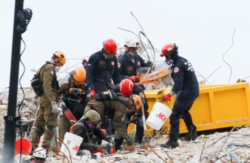 Emergency workers conduct search and rescue efforts at the site of a partially collapsed residential building in Surfside, near Miami Beach, Florida (photo credit: JOE SKIPPER/REUTERS)