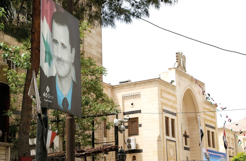 A PICTURE of Syria’s President Bashar Assad hangs outside the parliament building in Damascus in April. (photo credit: YAMAM AL SHAAR/REUTERS)