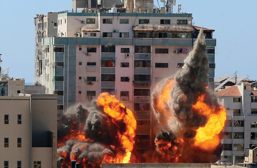 An explosion is seen near al-Jalaa Tower housing AP and Al Jazeera offices during Israeli missile strikes in Gaza City on May 15 (photo credit: ASHRAF ABU AMRAH / REUTERS)
