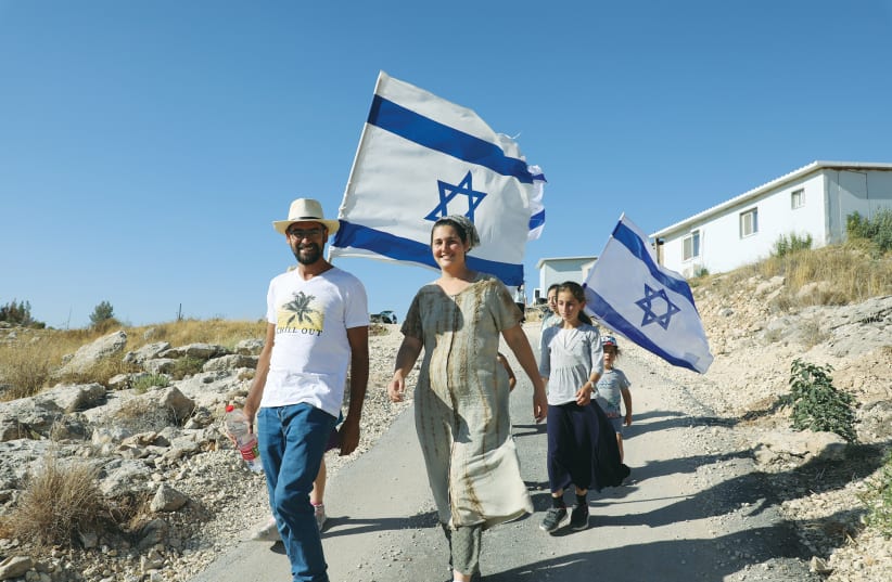 ISRAELIS WALK with flags in the Bat Ayin settlement in Gush Etzion on the West Bank, last month.  (photo credit: GERSHON ELINSON/FLASH90)
