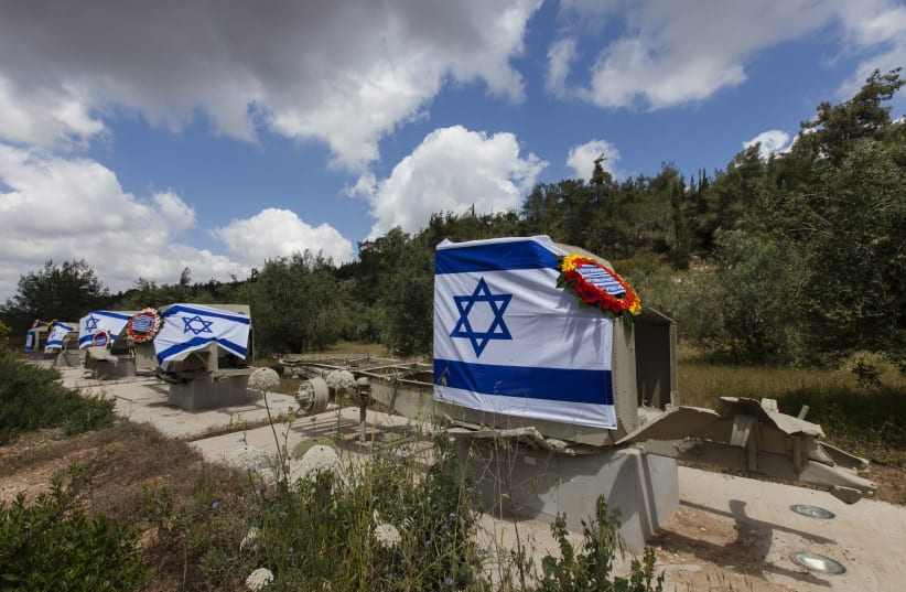 Israeli flags and wreaths are seen on the remains of armored military vehicles and cars, part of the armored convoy ruins at Sha'ar Hagai that were destroyed during Israel's War of Independence in 1948, near Shoresh, outside Jerusalem, on April 10, 2013. (photo credit: FLASH90)