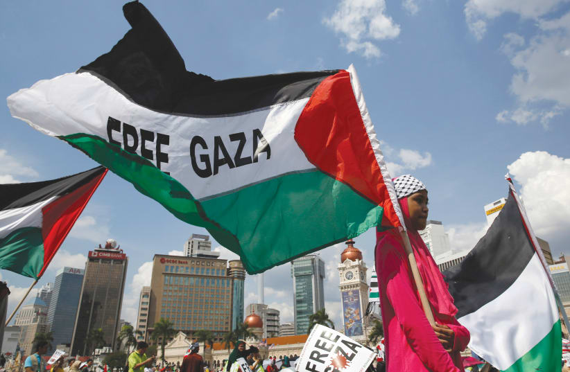 A GIRL holds a flag at a rally in support of Gaza in Kuala Lumpur. (photo credit: OLIVIA HARRIS/ REUTERS)