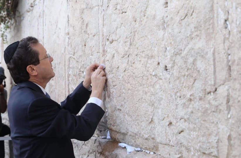 President-elect Isaac Herzog is seen putting a note into the Western Wall in Jerusalem's Old City, on July 6, 2021. (photo credit: MARC ISRAEL SELLEM/THE JERUSALEM POST)
