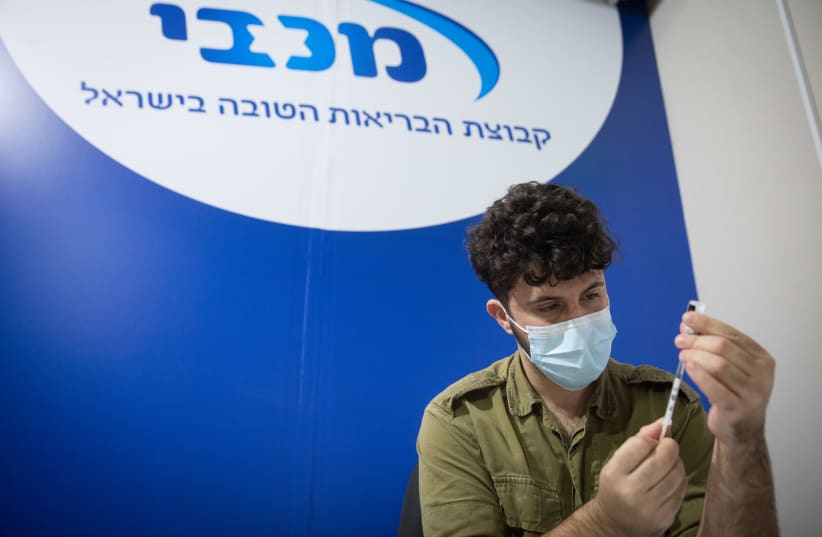 Israelis receive a COVID-19 vaccine, at a Maccabi Health vaccination center at the Givatayim mall, outside of Tel Aviv, January 20, 2021. (photo credit: MIRIAM ALSTER/FLASH90)