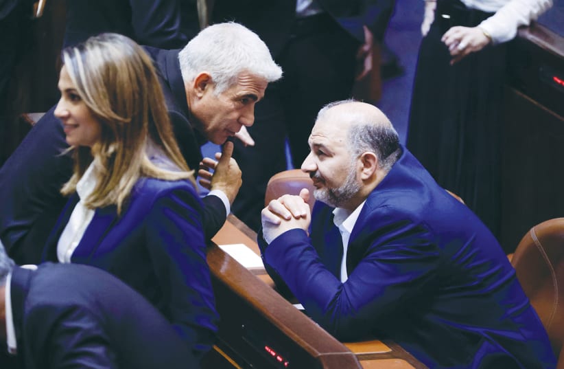 FOREIGN MINISTER Yair Lapid speaks with Ra’am Party leader Mansour Abbas in the Knesset last month. (photo credit: OLIVIER FITOUSSI/FLASH90)