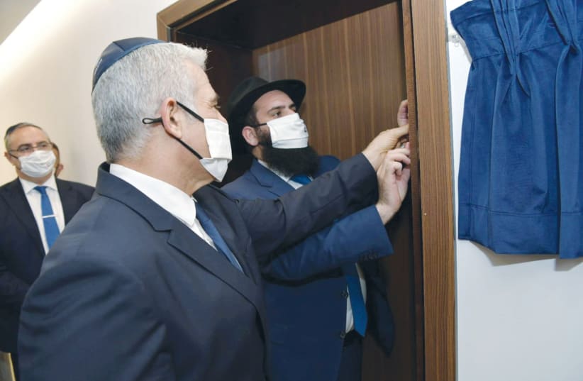 FOREIGN MINISTER Yair Lapid helps to affix a mezuzah to a doorpost of the Israeli Embassy in Abu Dhabi, UAE, last month. (photo credit: SHLOMI AMSALEM/GPO/REUTERS)