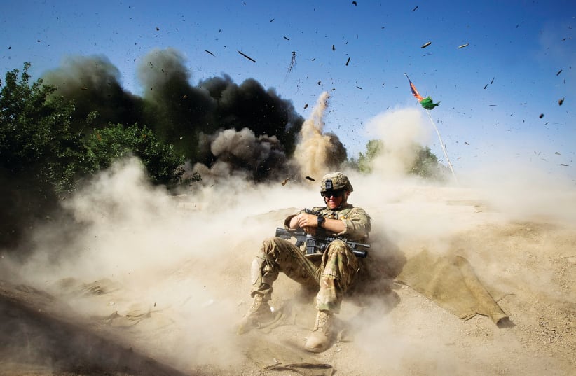 A US SOLDIER takes cover during a controlled detonation in southern Afghanistan’s Kandahar Province in 2012. (photo credit: SHAMIL ZHUMATOV / REUTERS)