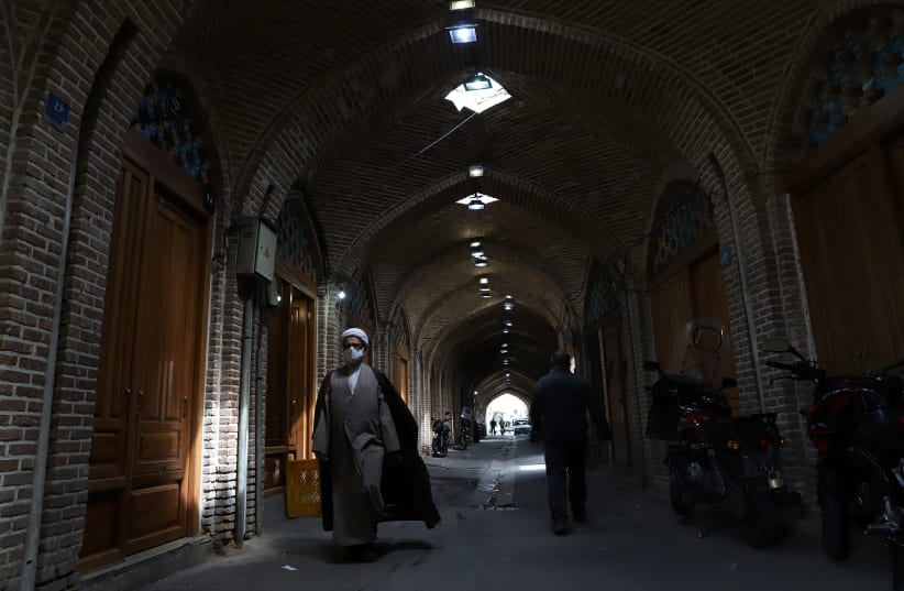 An Iranian cleric walks in front of closed shops in Tehran Bazaar following the tightening of restrictions to curb the surge of COVID-19 cases, Tehran, Iran April 10, 2021.  (photo credit: MAJID ASGARIPOUR/WANA (WEST ASIA NEWS AGENCY) VIA REUTERS)