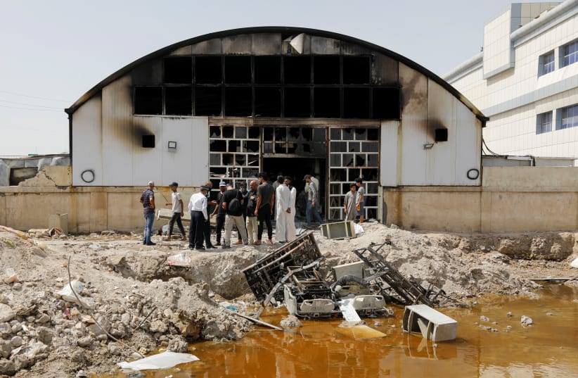 People gather as they inspect the damage at al-Hussain coronavirus hospital where a fire broke out, in Nassiriya, Iraq, July 13, 202 (photo credit: REUTERS/KHALID AL MOUSILY)