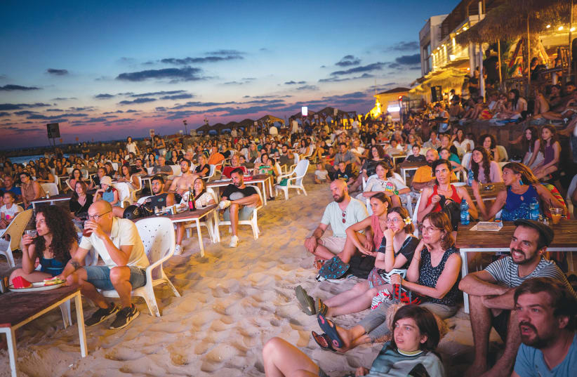 PEOPLE WATCH a movie screened as part of the DocAviv film festival, at the Hilton beach in Tel Aviv, last week. (photo credit: MIRIAM ALSTER/FLASH90)