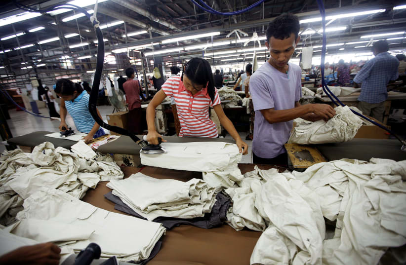 Workers iron and arrange clothing at a garment factory at Hlaing Taryar industrial zone in Yangon, March 10, 2010. (photo credit: REUTERS)