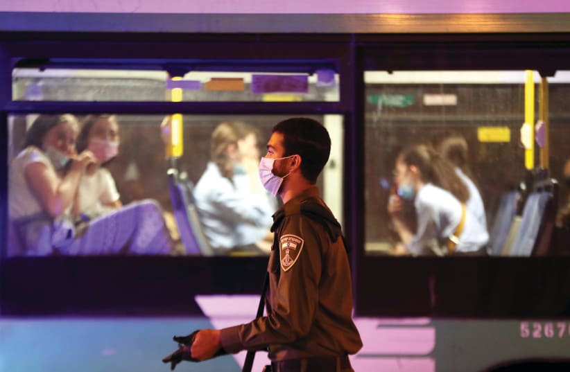 Two women look out of a bus as an Israel Police officer walks past. (photo credit: REUTERS)
