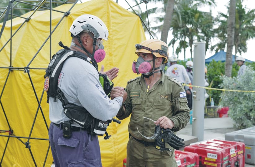 A MEMBER of the Miami-Dade Fire Department speaks with an Israeli rescue worker at the site of the collapsed condominium complex in Surfside, Florida, earlier this month. (photo credit: MDFD/REUTERS)