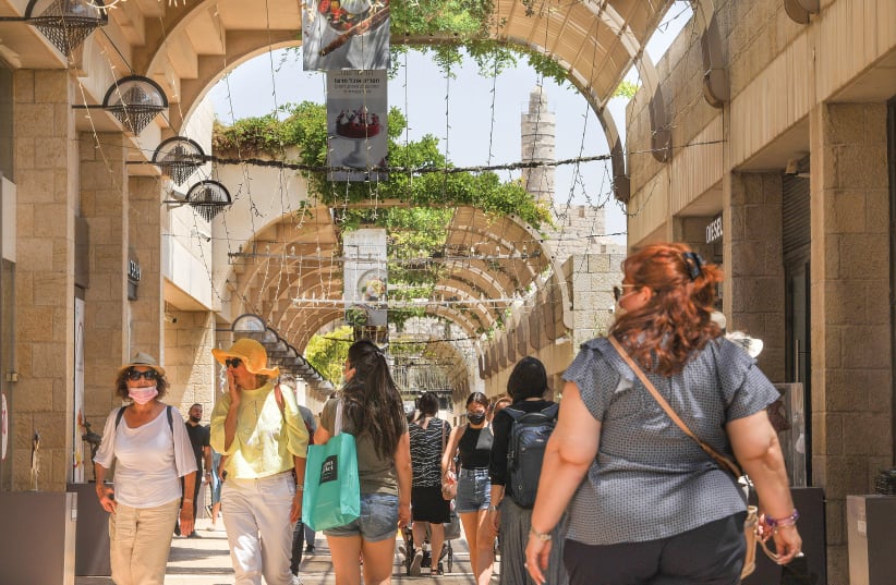 MASKED AND unmasked people walk along Jerusalem’s Mamilla pedestrian mall yesterday. (photo credit: MARC ISRAEL SELLEM/THE JERUSALEM POST)