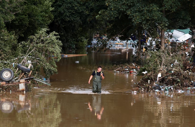 A man walks through the water in an area affected by floods following heavy rainfalls in Bad Neuenahr-Ahrweiler, Germany, July 15, 2021. (photo credit: REUTERS/WOLFGANG RATTAY)