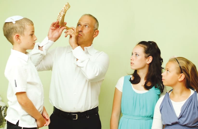 A man blows the shofar for his family, as is customary every morning during the month of Elul  (photo credit: MENDY HECHTMAN/FLASH90)