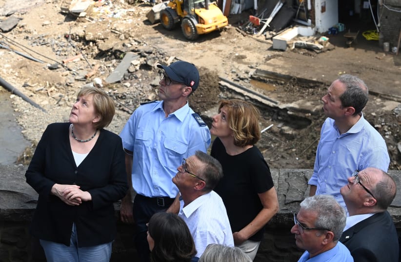 German Chancellor Angela Merkel (L) and Rhineland-Palatinate State Premier Malu Dreyer (3rd L) look up as they stand on a bridge during their visit in the flood-ravaged areas in Schuld near Bad Neuenahr-Ahrweiler, Rhineland-Palatinate state, Germany July 18, 2021 (photo credit: CHRISTOF STACHE/REUTERS)