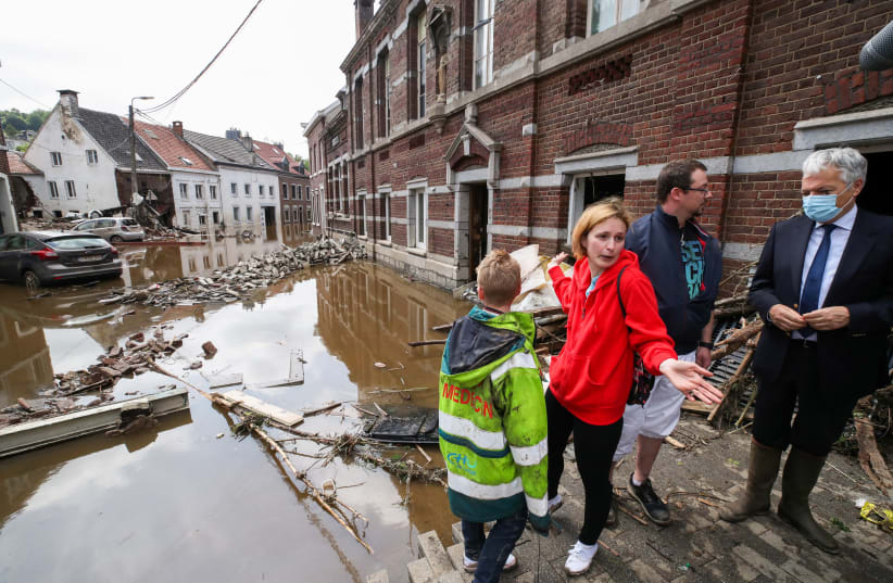 European Commissioner for Justice Didier Reynders speaks with Madeline Brasseur, 37, Paul Brasseur, 42, and their son Samuel, 12, at an area affected by floods, following heavy rainfalls, in Pepinster, Belgium, July 17, 2021 (photo credit: YVES HERMAN / REUTERS)