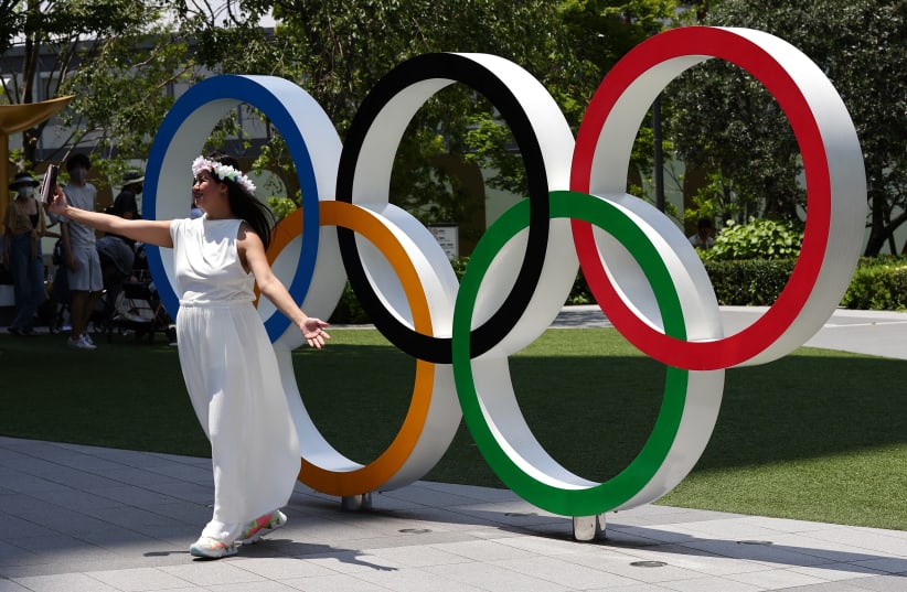 Maria Watanabe, a Filipino living in Japan takes a selfie in front of the Olympic Rings outside The National Stadium, the main venue of the Tokyo 2020 Olympic Games  (photo credit: REUTERS/KIM KYUNG-HOON)