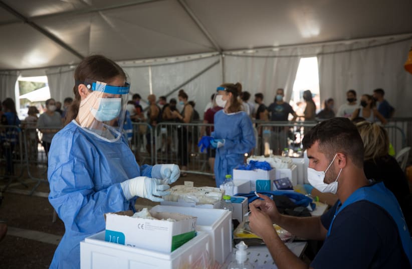 A technician collects swab samples for COVID-19, at a testing center run by the Tel Aviv municipality in cooperation with Tel haShomer hospital, at Rabin Square in Tel Aviv, on July 20, 2021. (photo credit: MIRIAM ALSTER/FLASH90)